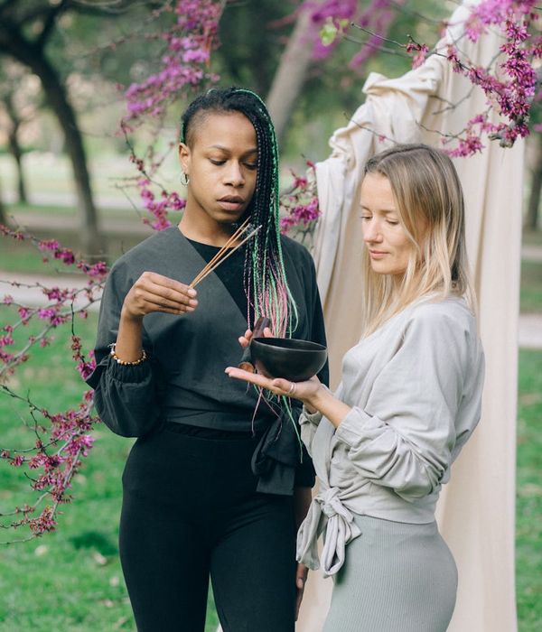 A woman in activewear smiling peacefully in a green park setting.